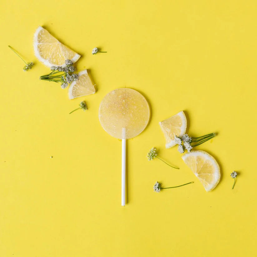 Lemon slices and a lemon candy on a yellow background