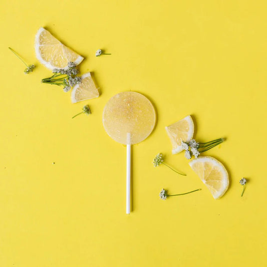 Lemon slices and a lemon candy on a yellow background