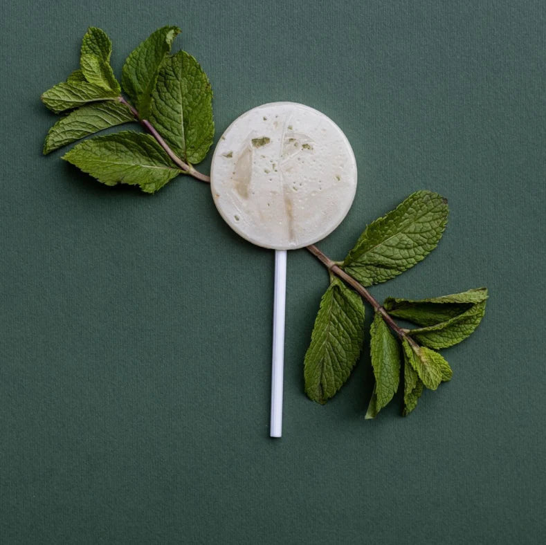 Mint leaf with a round mint candy on a green background