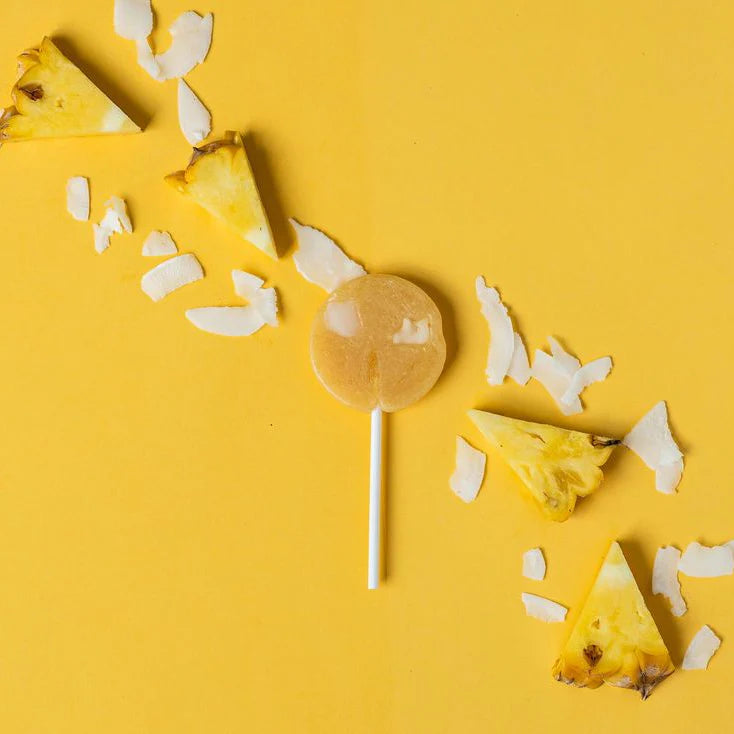 Pineapple slices and a lollipop on a yellow background