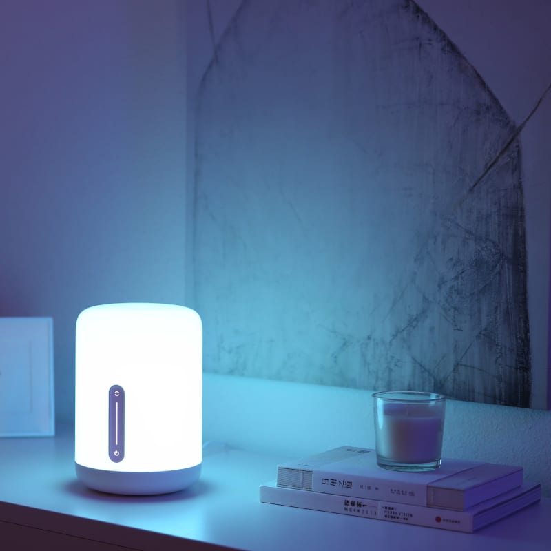 Smart light bulb on a shelf with books and a glass of milk in a dimly lit room
